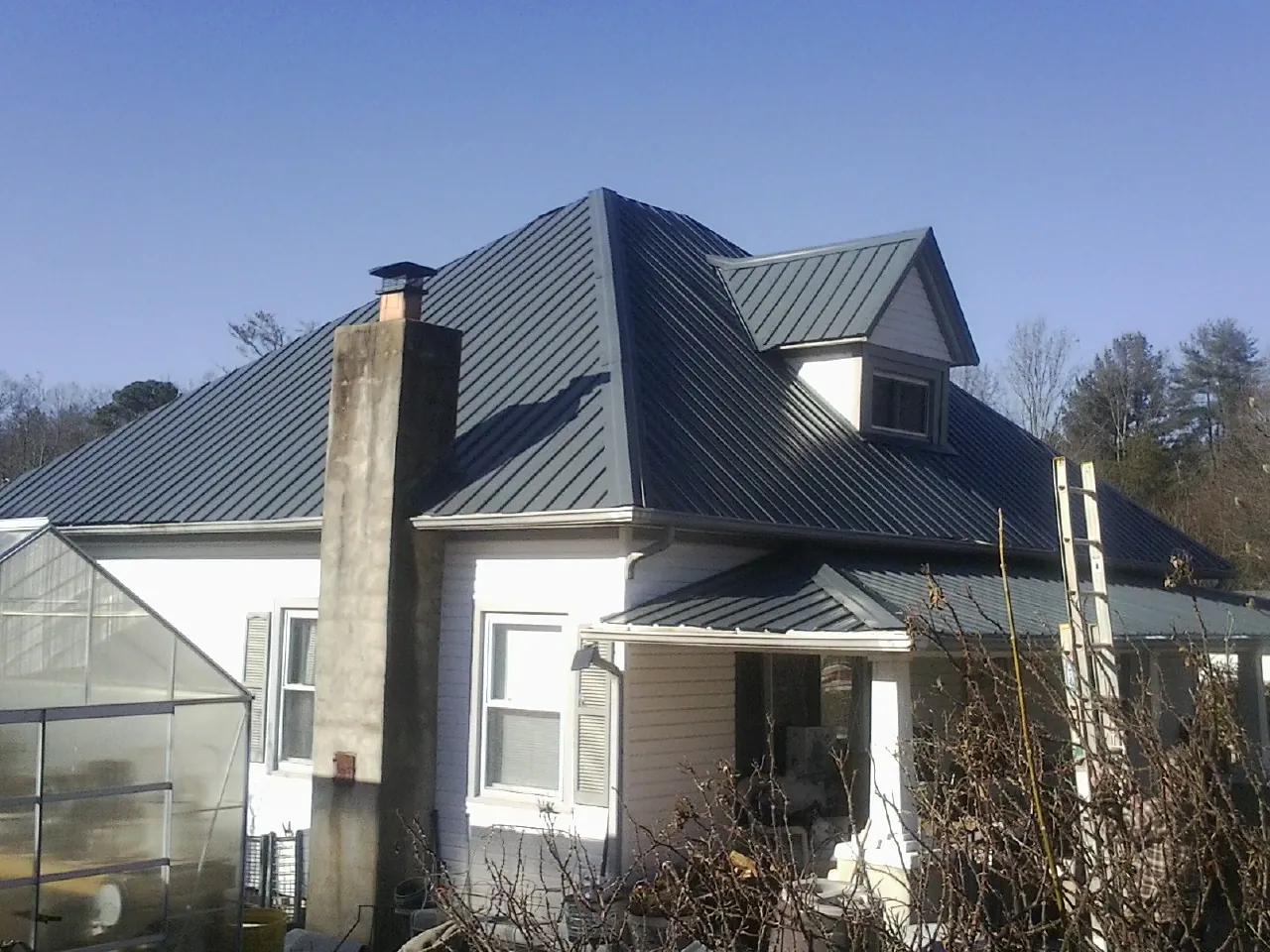 Dark blue standing seam metal roof on a white farmhouse with dormer — Slate & Tile Roof Repair by Roofing Brothers in Gate