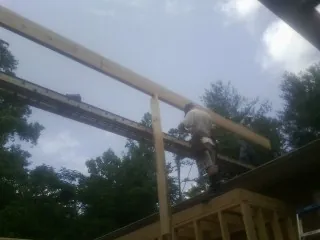 Carpenter setting a ridge beam over a new addition frame — Ice Dam Removal by Roofing Brothers in Gate