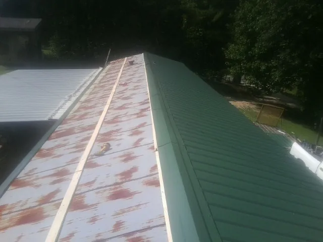 Old rusted panels beside newly installed green metal roofing — Wind Damage Roof Repair by Roofing Brothers in Gate