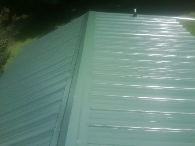 New green metal panels meeting at the ridge of a roof — Flat Roof Repair work by our crew in Gate