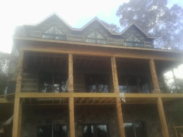 Dormers and porch framing on a large log home under construction — Roof Coating work by our crew in Gate