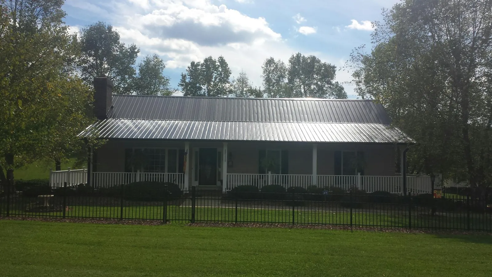 Gray metal roof on a brick ranch with a full width front porch — Gutter Guard Installation work by our crew in Gate